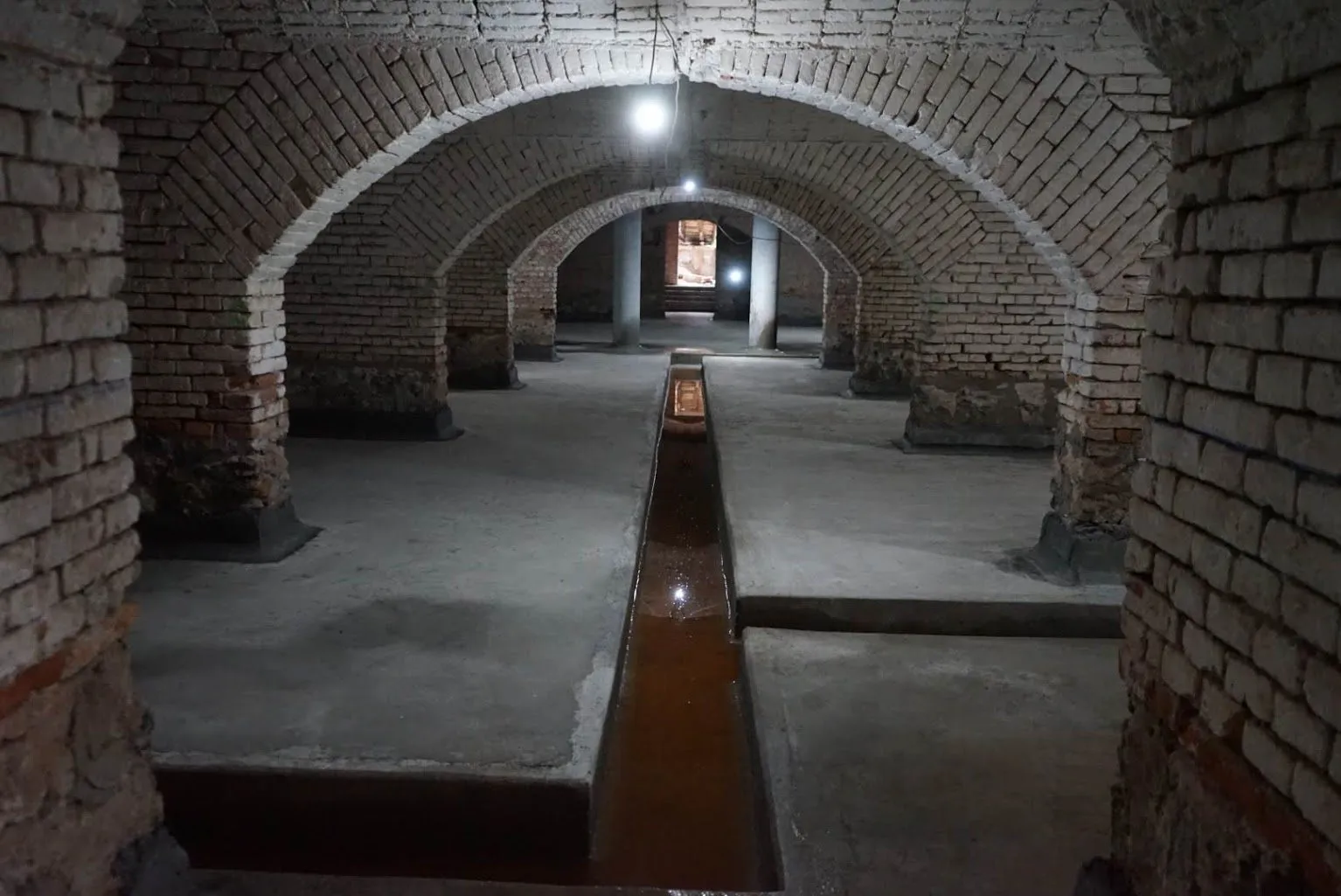 Demisolul cu bolți de cărămidă, curățat, cu un canal de drenaj prin mijlocul pardoselii