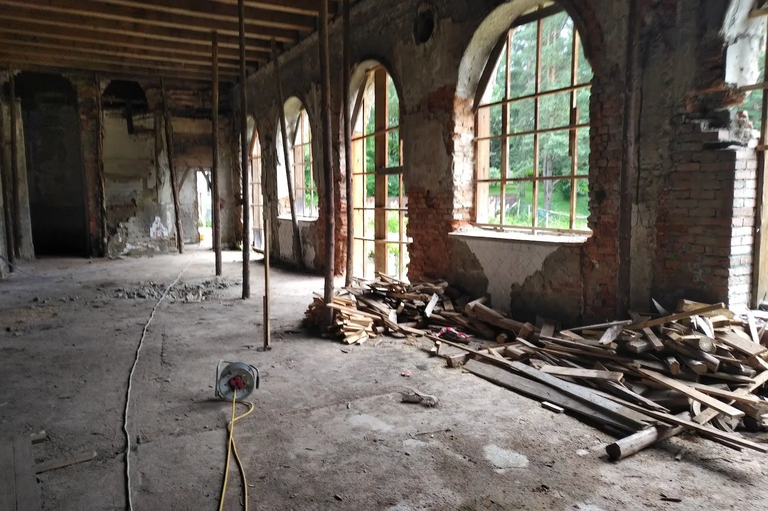 Galeria cu ferestre în arc, golită, cu proptele de lemn sub planșeu și grămezi de scânduri pe jos