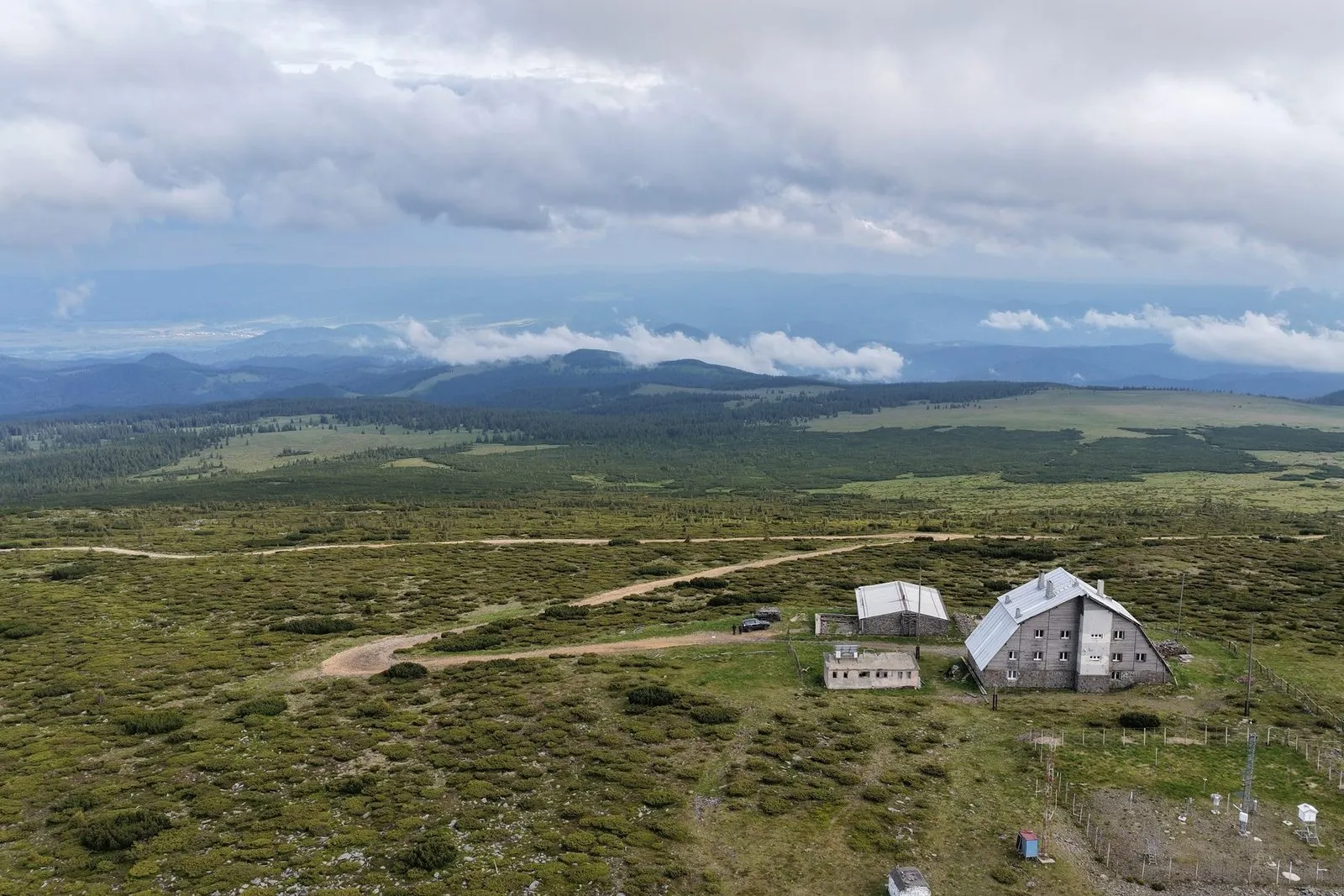 Vedere aeriană a stației meteorologice Călimani-Rețitiș, cu platforma de instrumente în prim-plan și munții în fundal