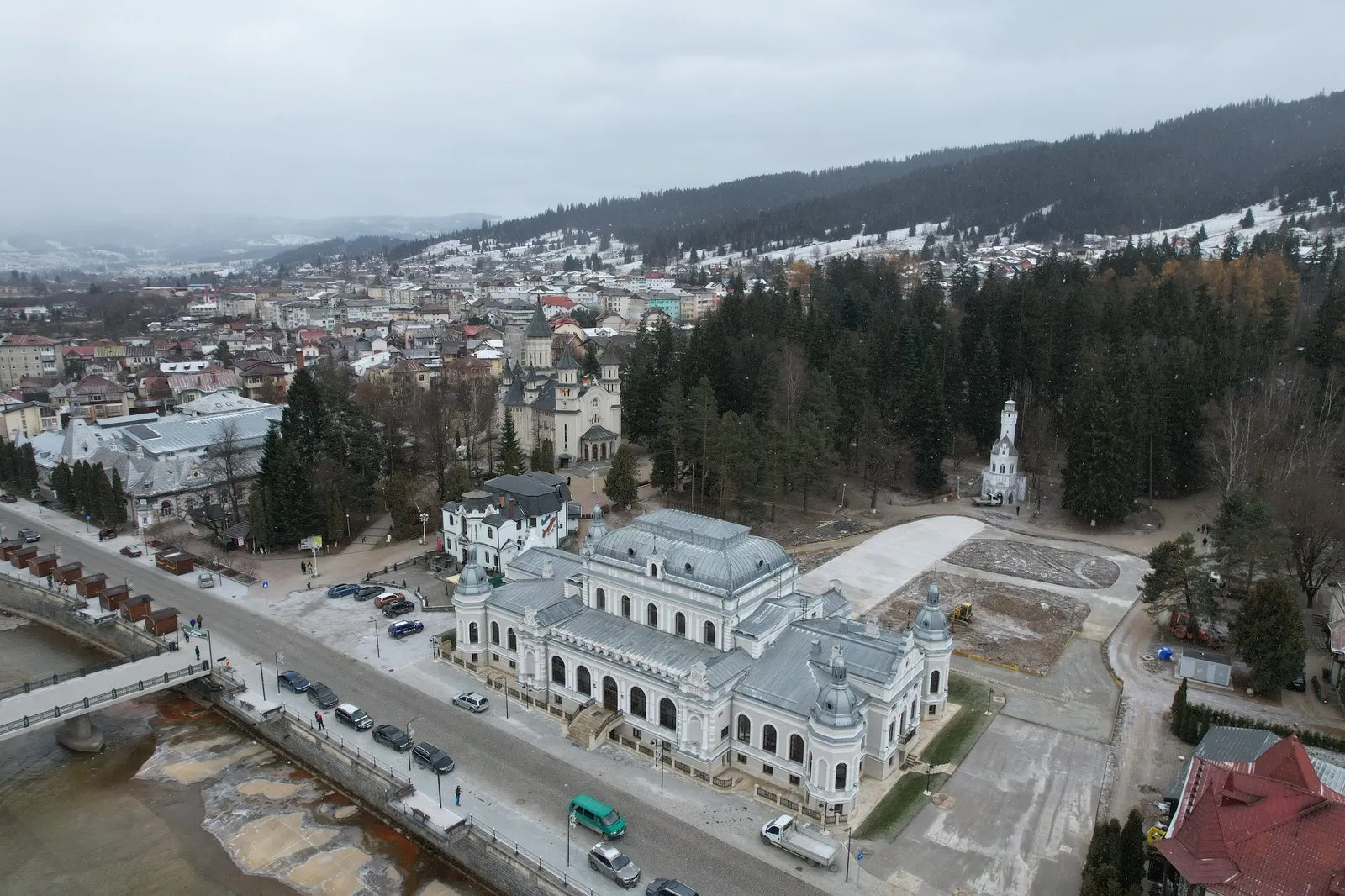 Vedere aeriană a Vatrei Dornei, cu Cazinoul Băilor alb în centru, parcul din spatele lui și dealurile împădurite, cu prima zăpadă